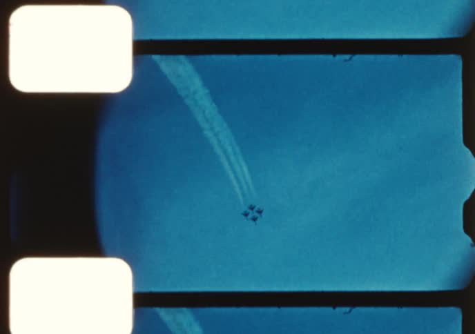 An aerobatic team performs maneuvers in formation, leaving smoke trails across the sky in this vintage 8mm film scan