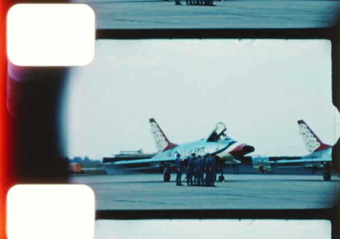 Vintage 8mm footage shows a U.S. Air Force Thunderbirds airshow with marching soldiers and jets on the tarmac