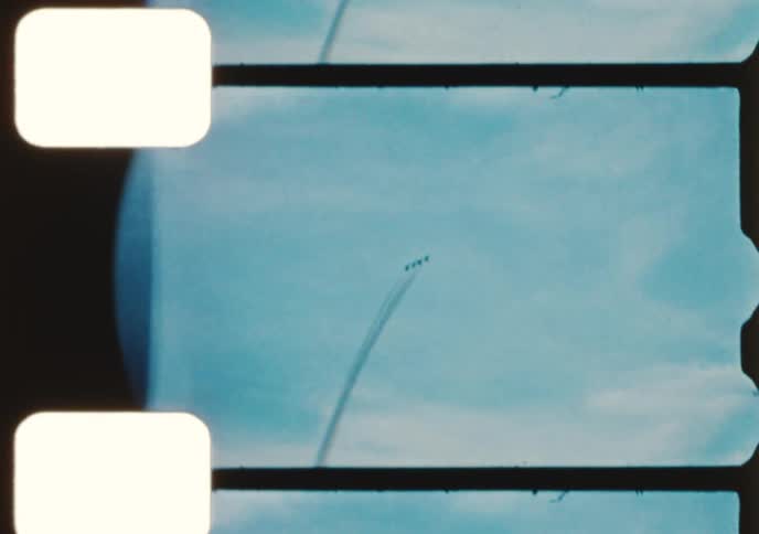 Vintage 8mm footage captures an exciting airshow with fighter jets performing aerial acrobatics and formation flying for a crowd