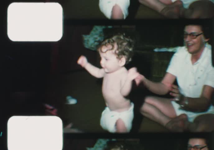 Vintage 8mm home movie footage shows a family encouraging a cute toddler to take his very first steps