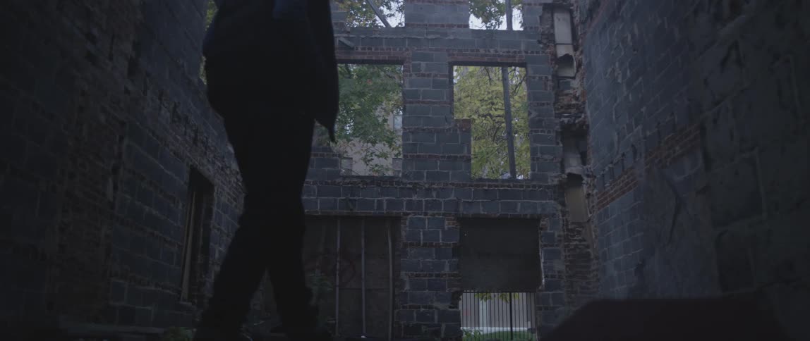A person walks through the remains of a building