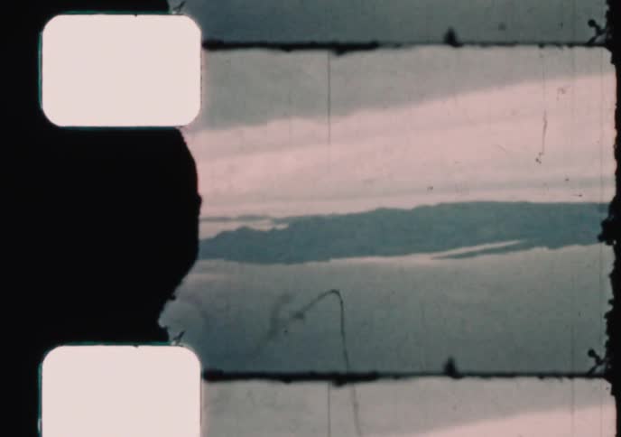 An aerial view of a vast coastline from an airplane window, captured on grainy and damaged vintage 8mm film