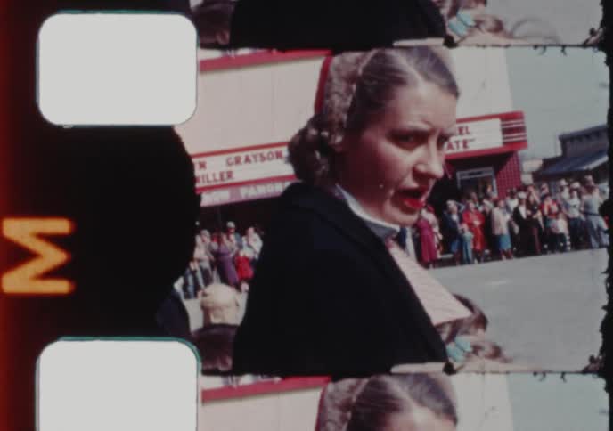 A woman smiles for the camera outside a crowded Plaza movie theater showing 'Kiss Me Kate' in the 1950s