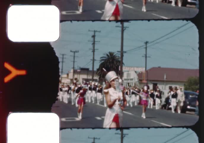 Vintage 8mm film captures a vibrant small town parade featuring majorettes twirling batons and a marching band