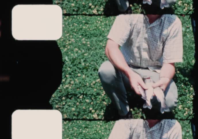 A vintage 8mm film captures two proud fishermen displaying their successful catch on a sunny day