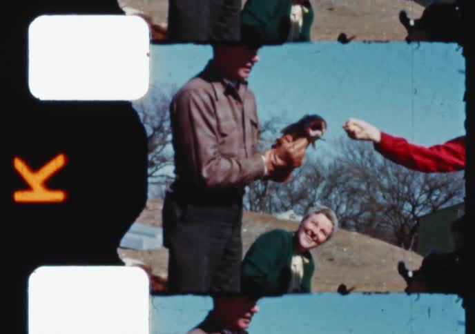 A family proudly displays a freshly caught bass fish in a nostalgic home movie from the 1960s