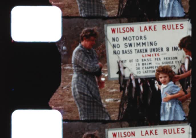 A vintage 1950s home movie shows a family proudly posing with their day's catch next to the Wilson Lake rules sign