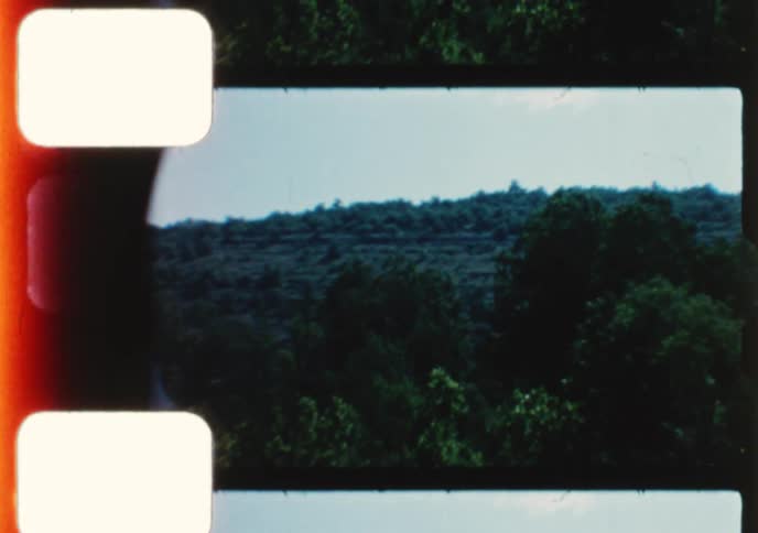 Vintage 8mm footage captures a serene boat ride along a tranquil, tree-lined river with a bridge visible in the distance