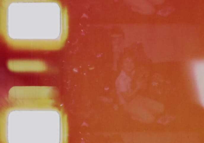 Heavily damaged vintage film strip reveals a faded image of a young girl with intense red and yellow light leaks and film grain