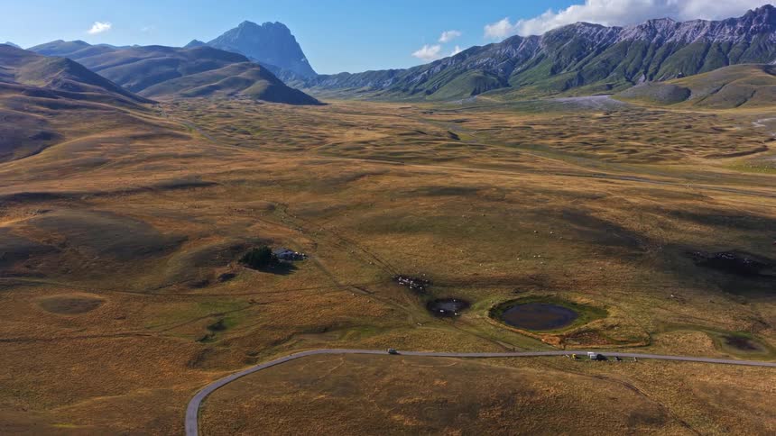 Stunning aerial footage reveals the majestic Gran Sasso mountains overlooking the vast golden plains of Campo Imperatore in Italy