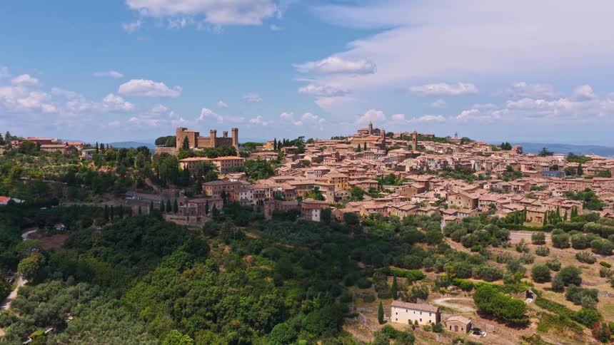 Stunning aerial ascent reveals the picturesque medieval town of Montalcino, nestled in the lush green hills of Tuscany, Italy