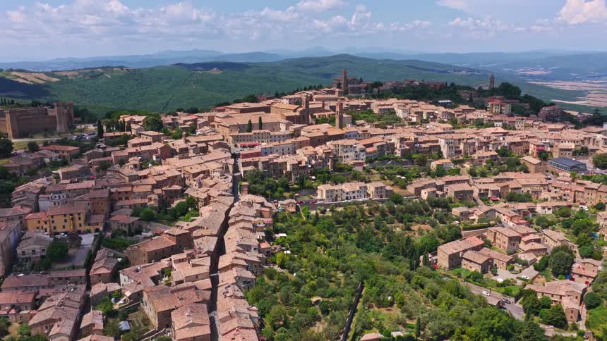 A scenic aerial flight towards the historic hilltop town of Montalcino in the heart of Tuscany, Italy, on a beautiful sunny day
