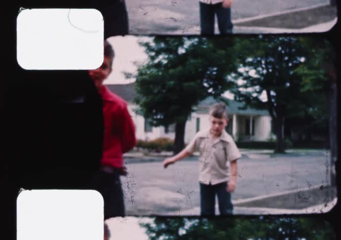 Vintage 8mm film captures precious childhood moments of children playing outside, including a toddler learning to walk and boys on roller skates