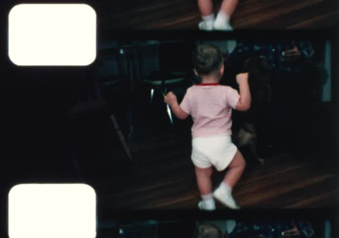 A charming 1960s home movie shows a smiling toddler playing with a ball before walking to his grandpa and the family dog