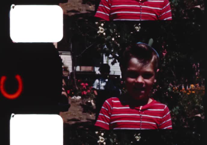 Charming 1950s home movie captures a young boy and his toddler sister walking hand-in-hand and the boy enjoying a red lollipop
