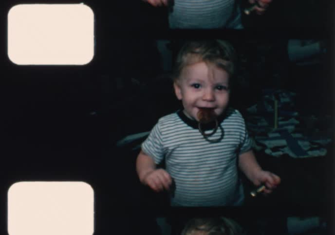 Vintage 8mm film captures a cute toddler playing with a pacifier and later making a happy mess while eating