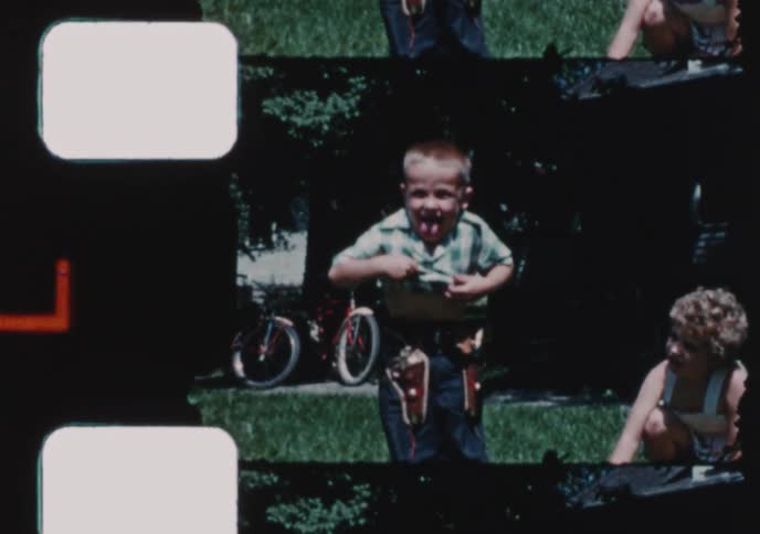 A nostalgic home movie captures boys playing in a yard, one doing a somersault and another in a cowboy costume, with a final scene showing the family's vintage car