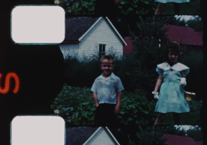 A charming vintage home movie from the 1950s captures a brother and sister dressed up for Easter, walking through a gate and hunting for eggs in the yard