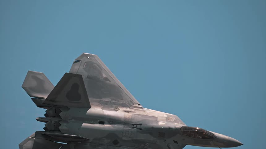A majestic F-22 Raptor glides through the sky in extreme slow motion, its powerful form creating vapor trails before the afterburner ignites