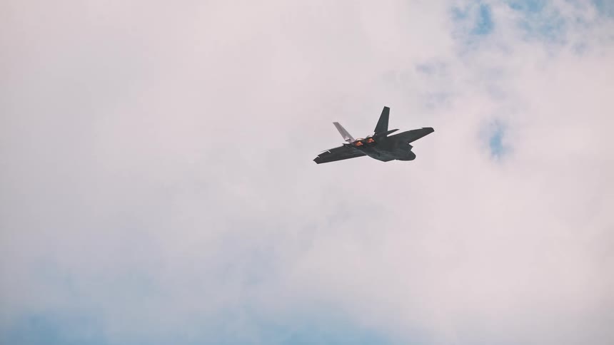 A futuristic animated stealth fighter jet soars through the sky with its afterburners blazing in slow motion
