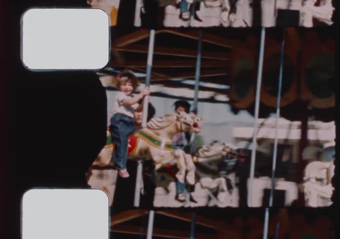 Vintage 8mm footage captures a mother and her children happily riding a classic carousel at an amusement park