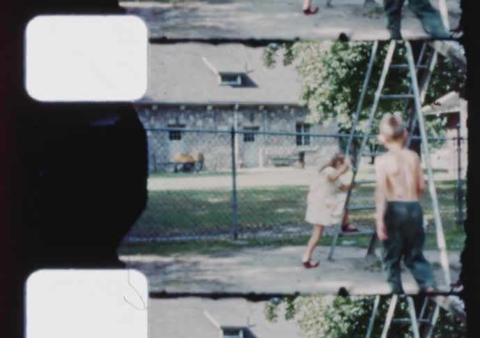 Vintage 1950s footage of a young boy and girl playing together on a sunny day at a park playground