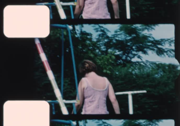 Archival footage shows a cute toddler and his mother playing on a swing set in their grassy backyard in the 1970s
