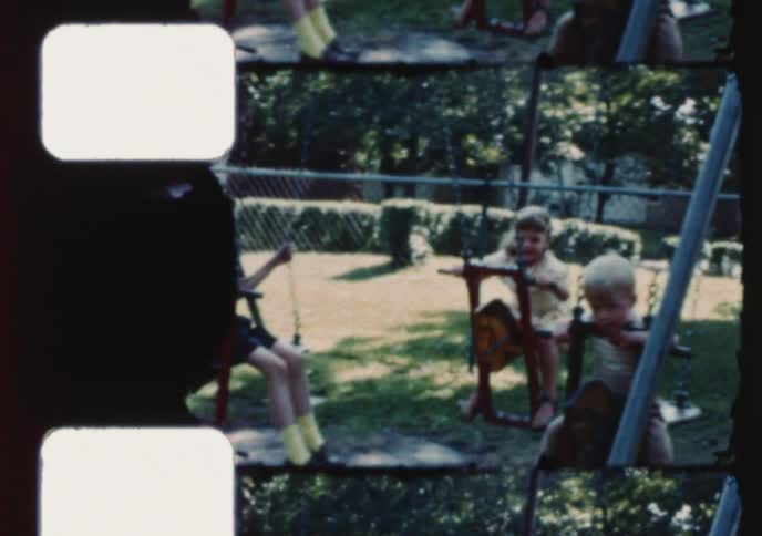Nostalgic vintage footage shows a group of young children having fun on a swing set in their backyard on a sunny day