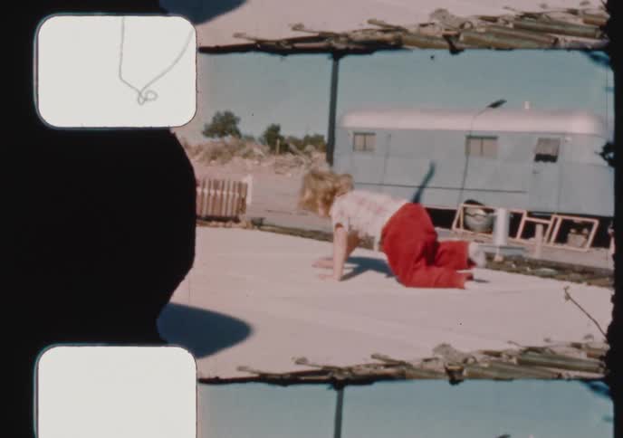A charming vintage home movie captures two joyful children with boundless energy jumping and playing outdoors