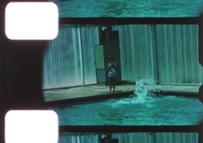 Vintage 8mm footage shows children and adults enjoying a day at a mid-century indoor swimming pool