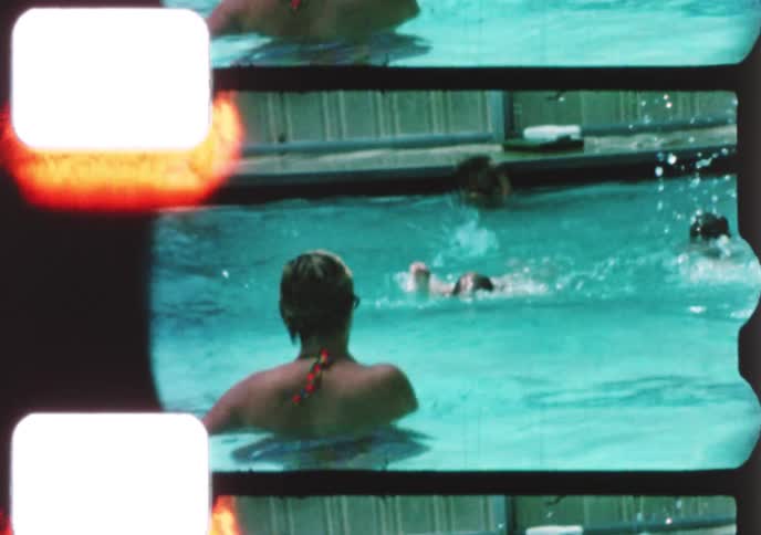 Vintage 8mm home movie captures a young boy jumping into a swimming pool with his family