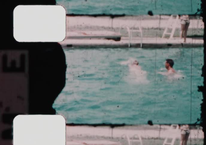 A father and his sons enjoy a sunny day swimming and playing together in a pool in this authentic vintage home movie