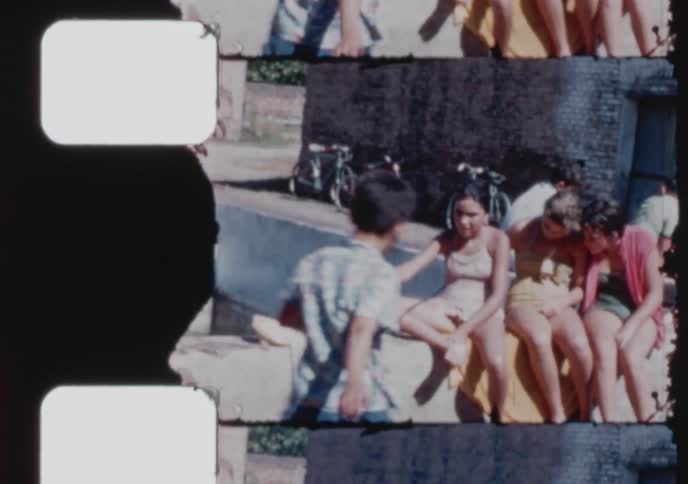 A group of happy teenagers and children in swimwear socialize by a pool on a sunny day in a vintage home movie