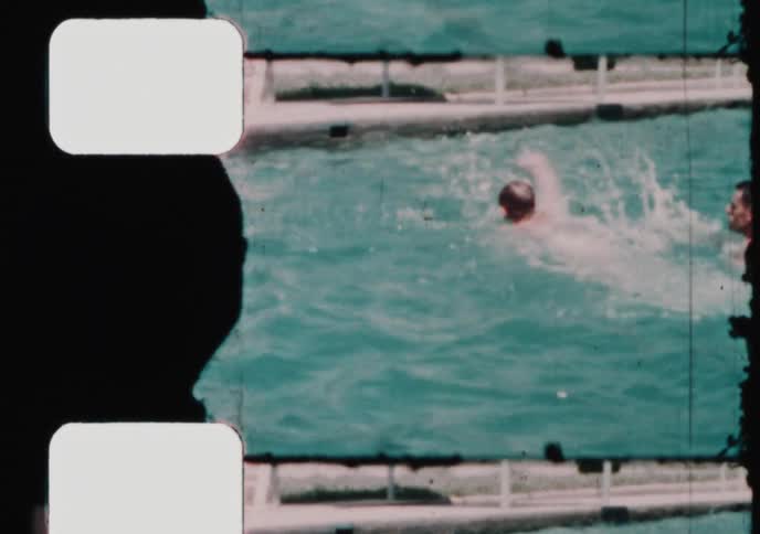 An authentic 8mm home movie captures a father teaching his young son to swim in a bright blue pool