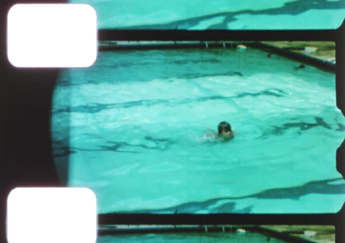 Vintage 8mm footage captures children and an adult swimming and playing in a sunny backyard pool