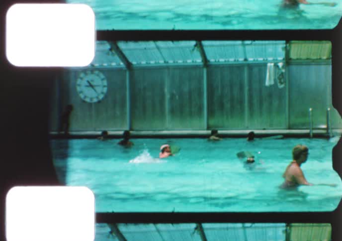 Vintage home movie captures children learning to swim and playing in a covered community pool