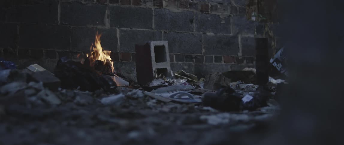 A fire buns near a brick wall
