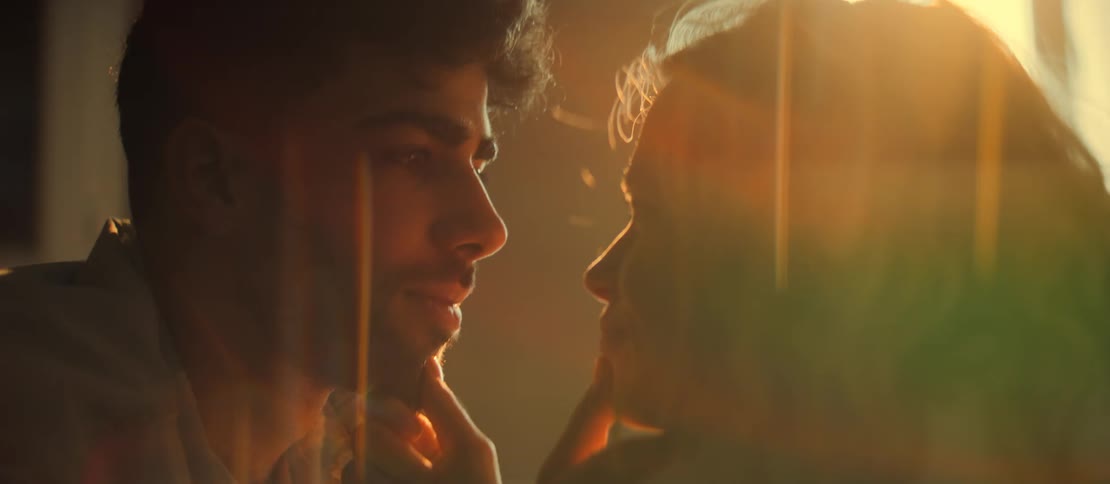 A romantic couple shares an intimate moment as they gaze into each other's eyes, bathed in the warm glow of sunset