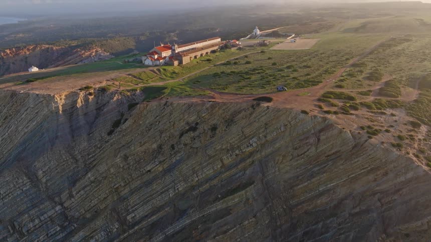 An aerial view reveals the stunning layered cliffs and the Santuário do Cabo Espichel in Portugal at sunrise