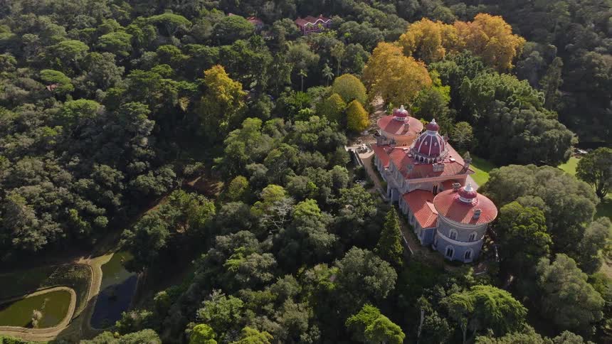 An aerial view reveals the breathtaking Monserrate Palace with its distinctive red domes, secluded within a vast and dense forest