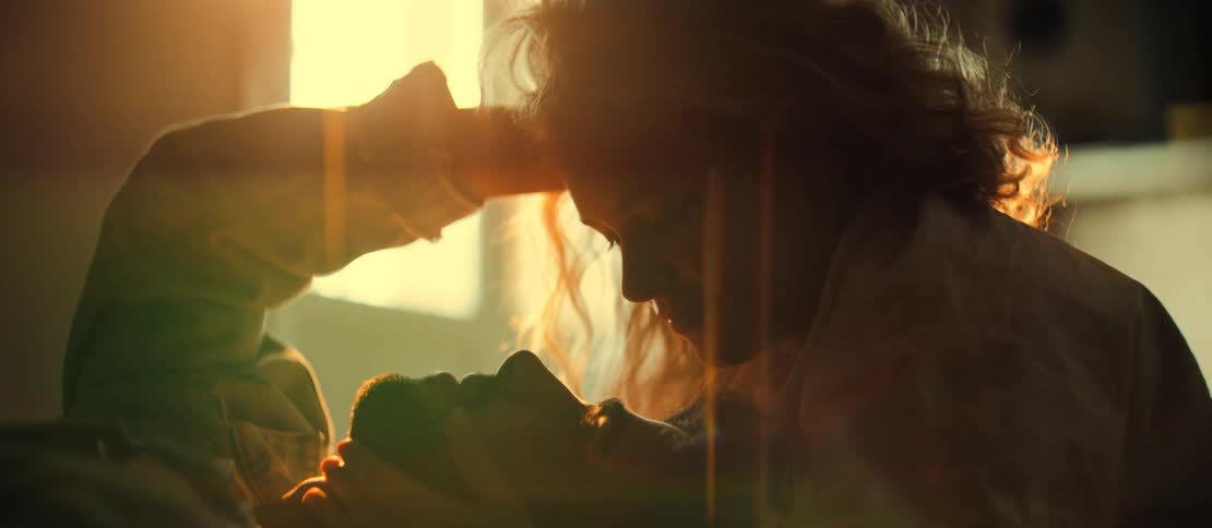 A silhouetted couple shares an intimate and tender moment, bathed in the warm, golden light of a sunrise