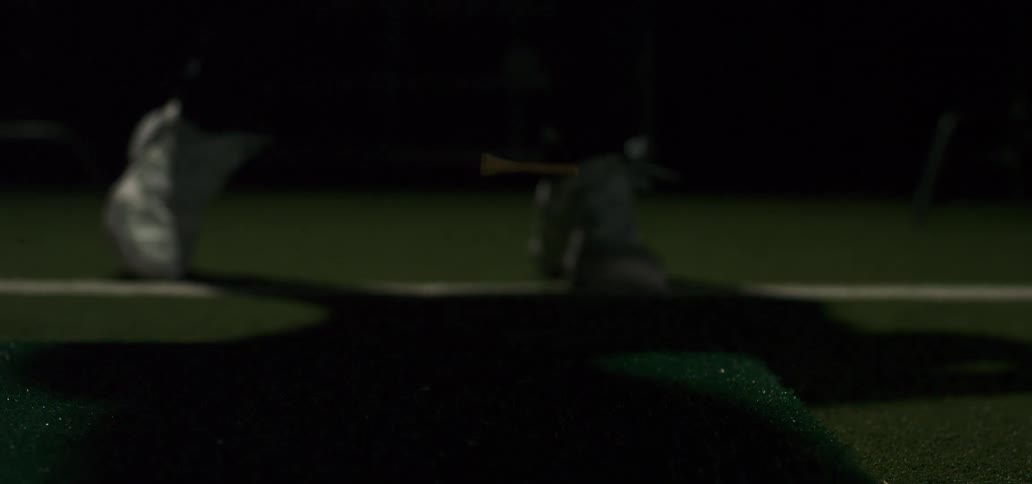 Super slow motion close-up of a driver hitting a golf ball off a tee at a driving range at night