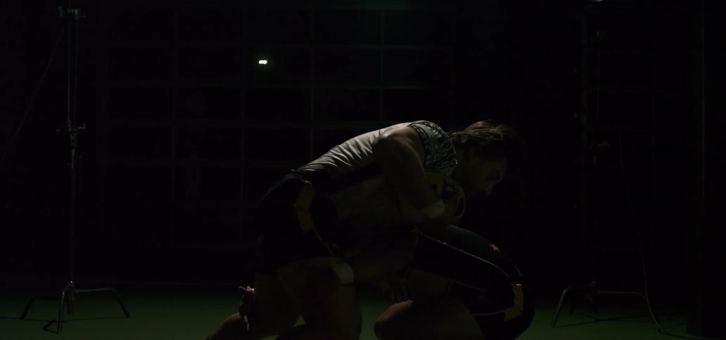 Two muscular rugby players face off in a dramatic, slow-motion tackle under flashing studio lights