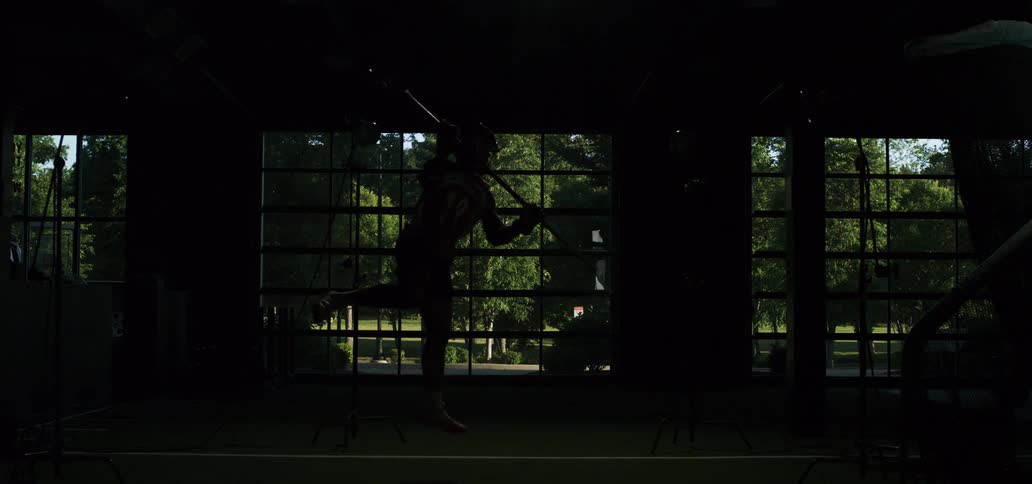 A lacrosse player is dramatically illuminated by a strobe light mid-air as he takes a powerful jump shot in super slow motion