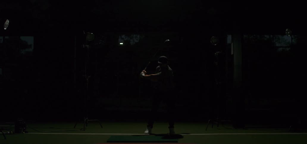 Dramatic super slow motion shot of a man hitting a golf ball with a club indoors with flash lighting