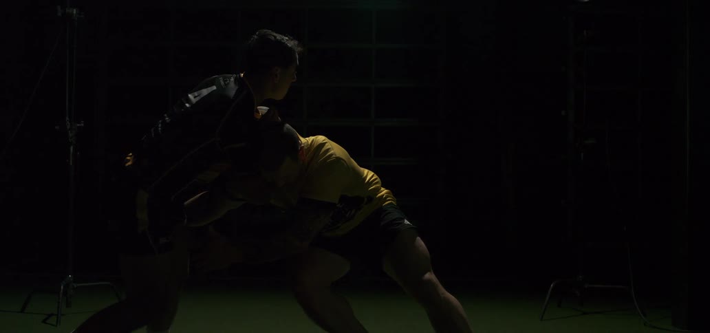 Two powerful rugby players are locked in a dramatic tackle in slow motion, illuminated by flashing studio lights