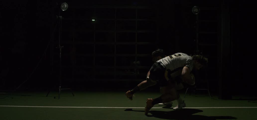 A rugby player gets tackled by an opponent in a powerful, slow-motion sequence under dramatic studio lighting