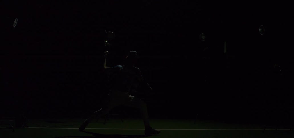 A baseball pitcher throws a ball in dramatic slow motion as bright lights flash on and off