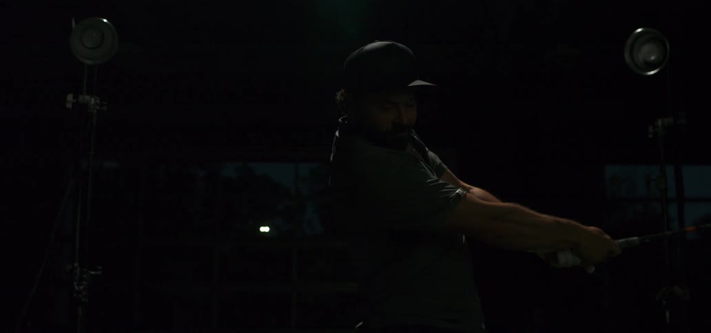 A male golfer in a dark room executes a powerful swing with a driver in super slow motion, highlighted by dramatic flashing lights
