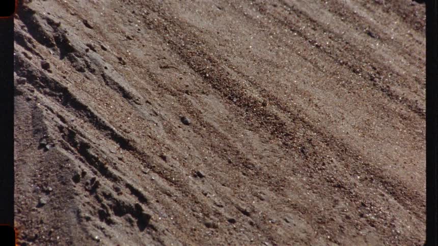 Extreme close-up vintage footage shows sparkling grains of sand sliding down a slope